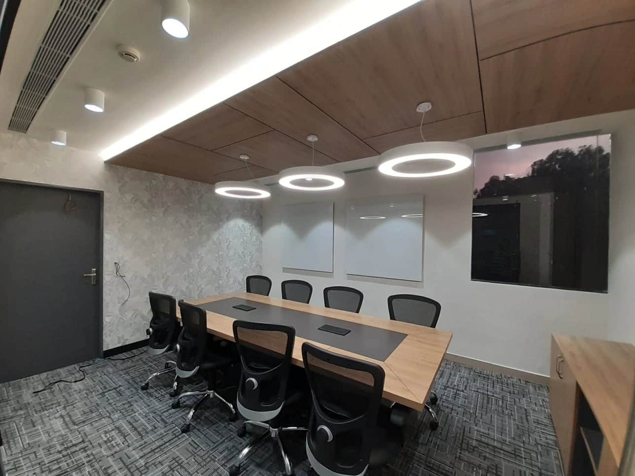 Discussion room with large conference table, ergonomic chairs, and modern lighting